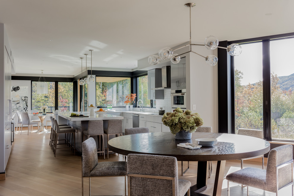 Esempio di una sala da pranzo aperta verso la cucina contemporanea con pareti bianche, parquet chiaro e pavimento beige