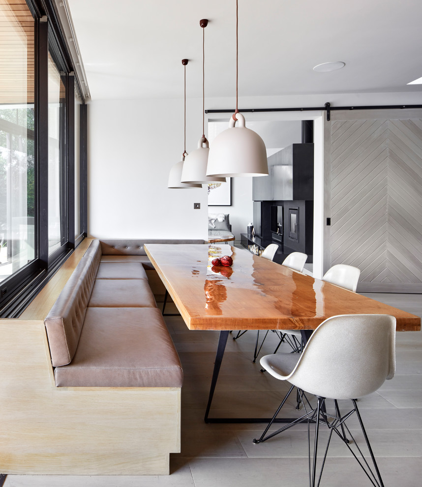 Immagine di una sala da pranzo aperta verso la cucina minimal con pareti bianche, parquet chiaro e pavimento grigio