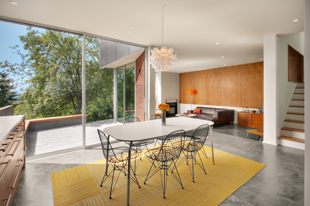 Foto di una sala da pranzo aperta verso il soggiorno minimalista di medie dimensioni con pareti bianche e pavimento in cemento