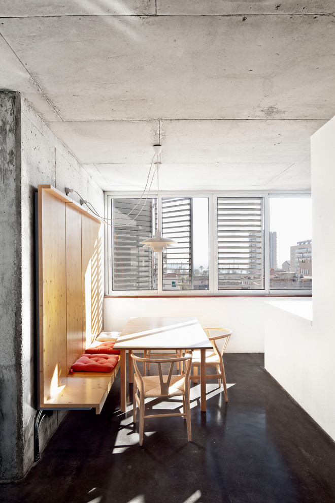 Cette photo montre une salle à manger ouverte sur la cuisine industrielle de taille moyenne avec un mur blanc, sol en béton ciré et aucune cheminée.