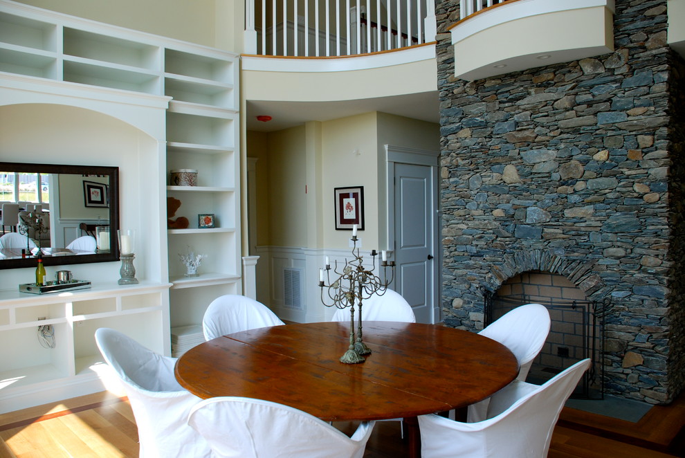 Aménagement d'une salle à manger classique fermée et de taille moyenne avec un mur beige, un sol en bois brun, une cheminée standard, un manteau de cheminée en pierre et un sol marron.