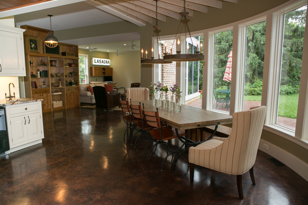 Foto di una grande sala da pranzo aperta verso il soggiorno classica con pareti verdi e pavimento in cemento