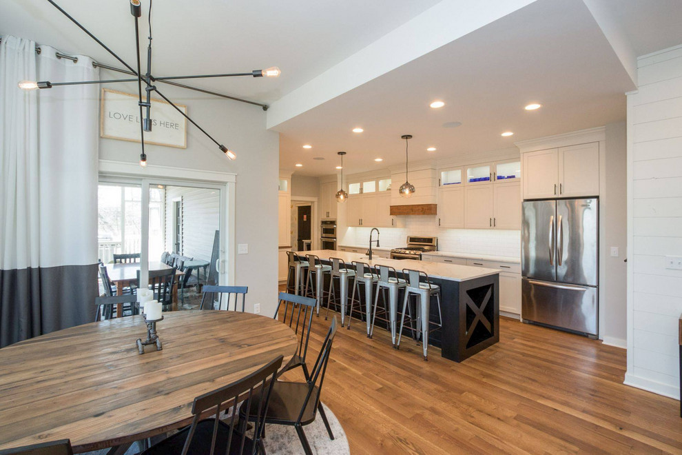 Immagine di una piccola sala da pranzo aperta verso il soggiorno country con pareti bianche, pavimento in legno massello medio e pavimento marrone