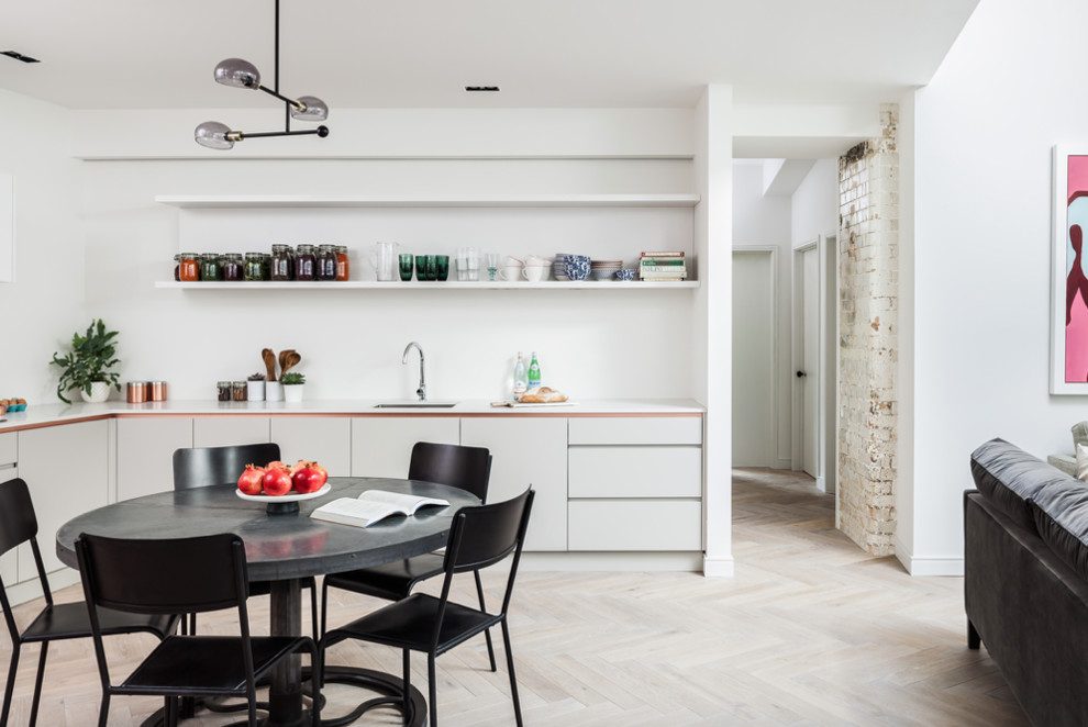 Example of a mid-sized trendy light wood floor and white floor kitchen/dining room combo design in London with white walls