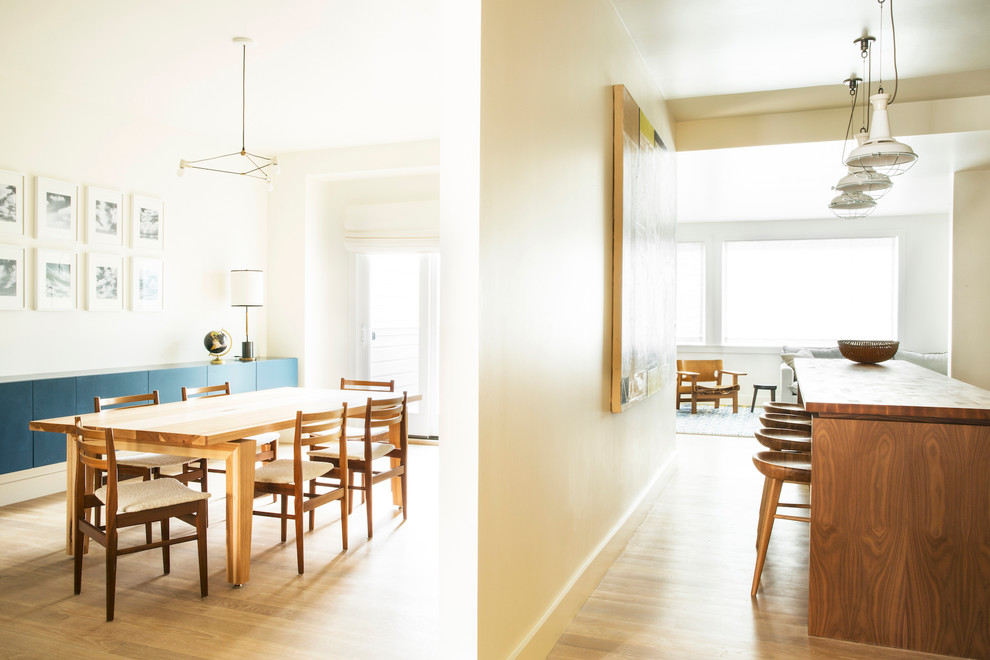 Immagine di una grande sala da pranzo aperta verso la cucina minimal con parquet chiaro