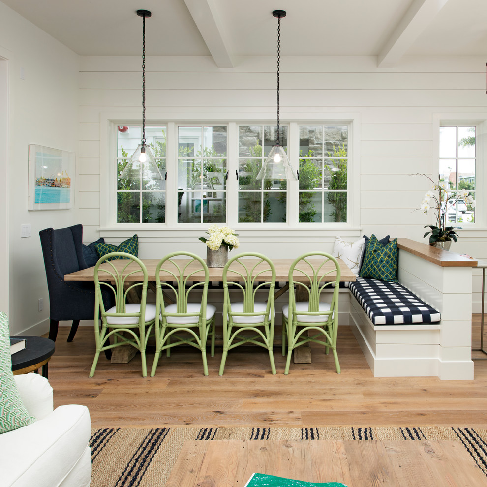 Immagine di una grande sala da pranzo aperta verso il soggiorno stile marino con pareti bianche e parquet chiaro