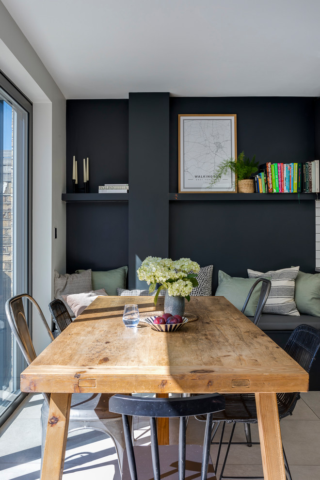 Example of a trendy ceramic tile and gray floor dining room design in London with black walls
