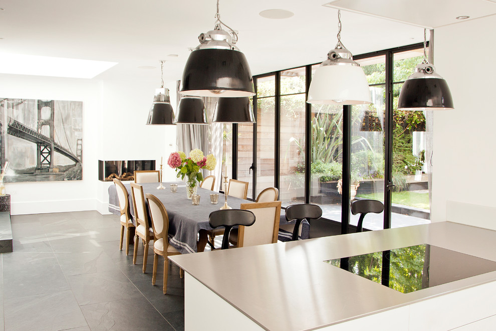 Ispirazione per una grande sala da pranzo aperta verso la cucina minimal con pareti bianche, pavimento grigio e camino ad angolo