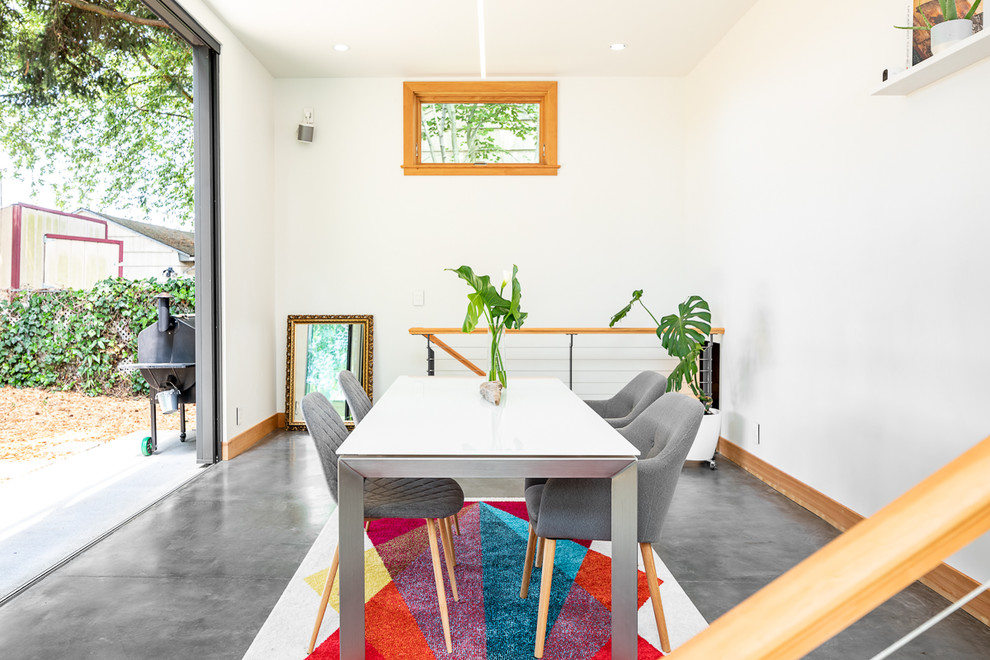 Diseño de comedor minimalista pequeño abierto con paredes blancas, suelo de cemento y suelo gris