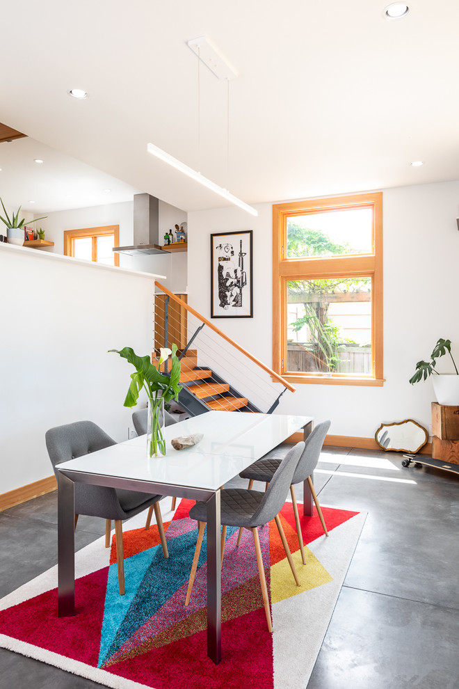 На фото: маленькая гостиная-столовая в современном стиле с белыми стенами, бетонным полом и серым полом для на участке и в саду с