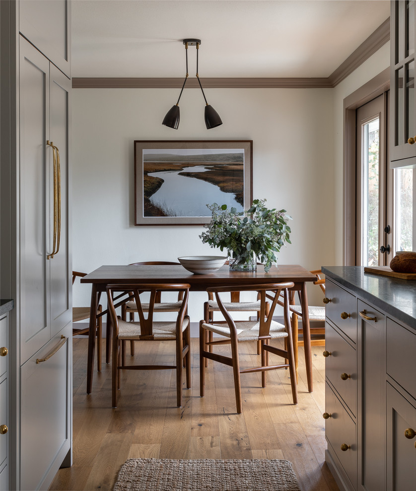 Idée de décoration pour une salle à manger ouverte sur la cuisine tradition avec un mur blanc, un sol en bois brun et un sol marron.
