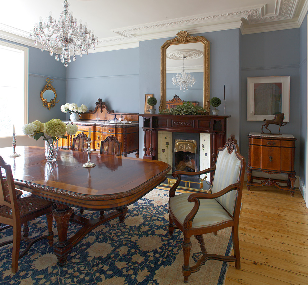 Esempio di una sala da pranzo classica con pareti blu, pavimento in legno massello medio e camino classico