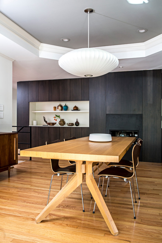 Idée de décoration pour une salle à manger ouverte sur la cuisine minimaliste de taille moyenne avec un mur multicolore, parquet clair, une cheminée ribbon, un manteau de cheminée en métal et un sol marron.