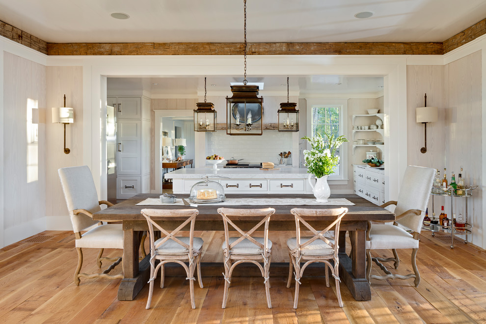 Cette image montre une salle à manger ouverte sur la cuisine chalet avec un mur beige, un sol en bois brun et aucune cheminée.