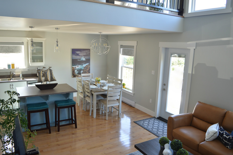 Foto di una sala da pranzo aperta verso la cucina costiera di medie dimensioni con pareti grigie, parquet chiaro, pavimento beige e soffitto a volta