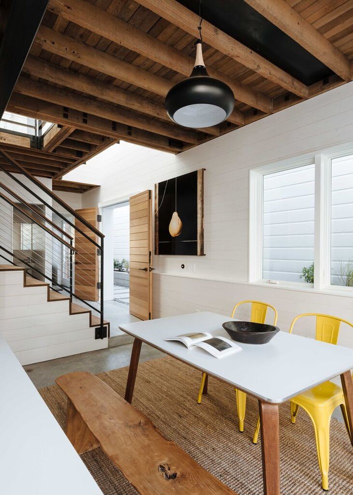 Immagine di una sala da pranzo aperta verso il soggiorno design di medie dimensioni con pareti bianche e pavimento in cemento