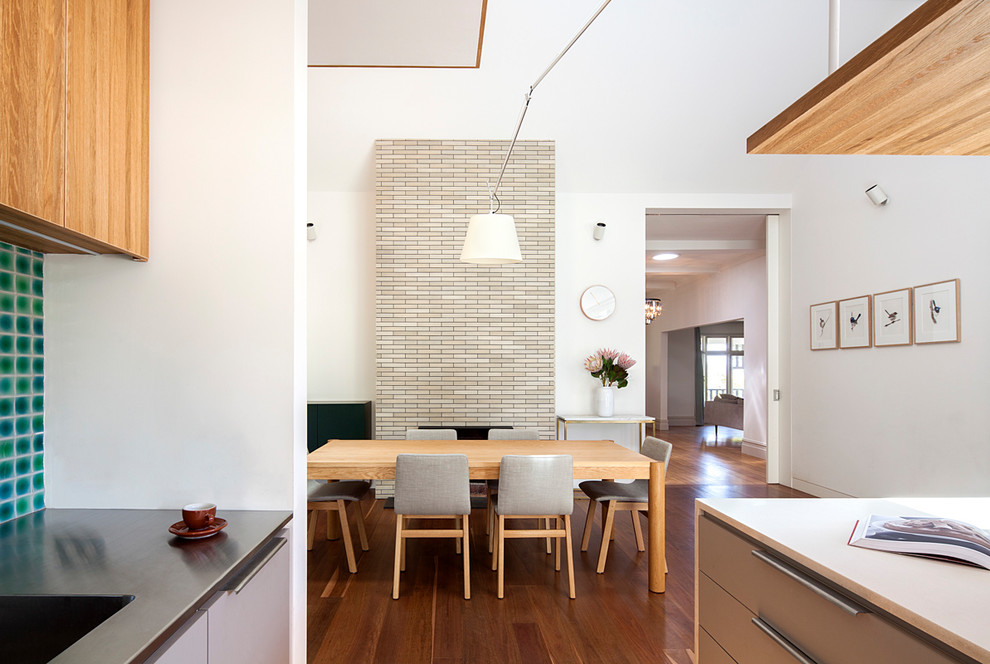 Cette image montre une salle à manger ouverte sur le salon design avec un mur blanc, parquet foncé et un sol marron.
