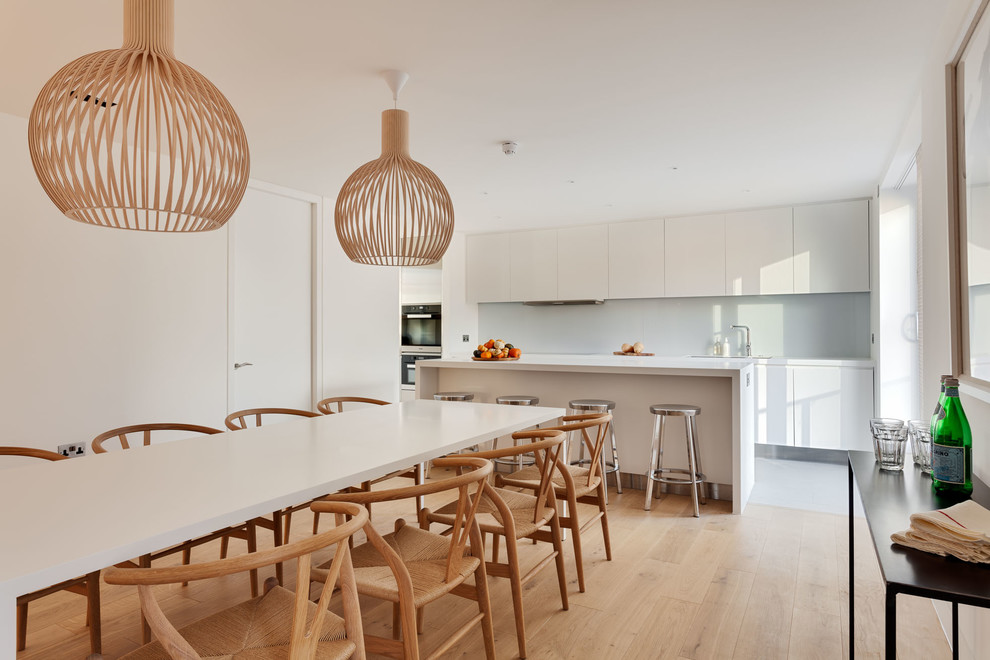 Свежая идея для дизайна: кухня-столовая в современном стиле с белыми стенами, светлым паркетным полом и стандартным камином - отличное фото интерьера