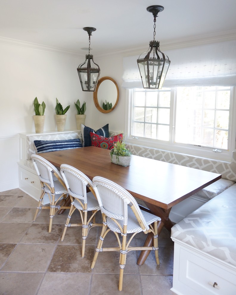 Cette image montre une salle à manger ouverte sur la cuisine rustique de taille moyenne avec un mur blanc et un sol en travertin.