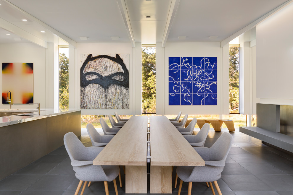 Cette photo montre une grande salle à manger ouverte sur la cuisine moderne avec un mur blanc et un sol gris.