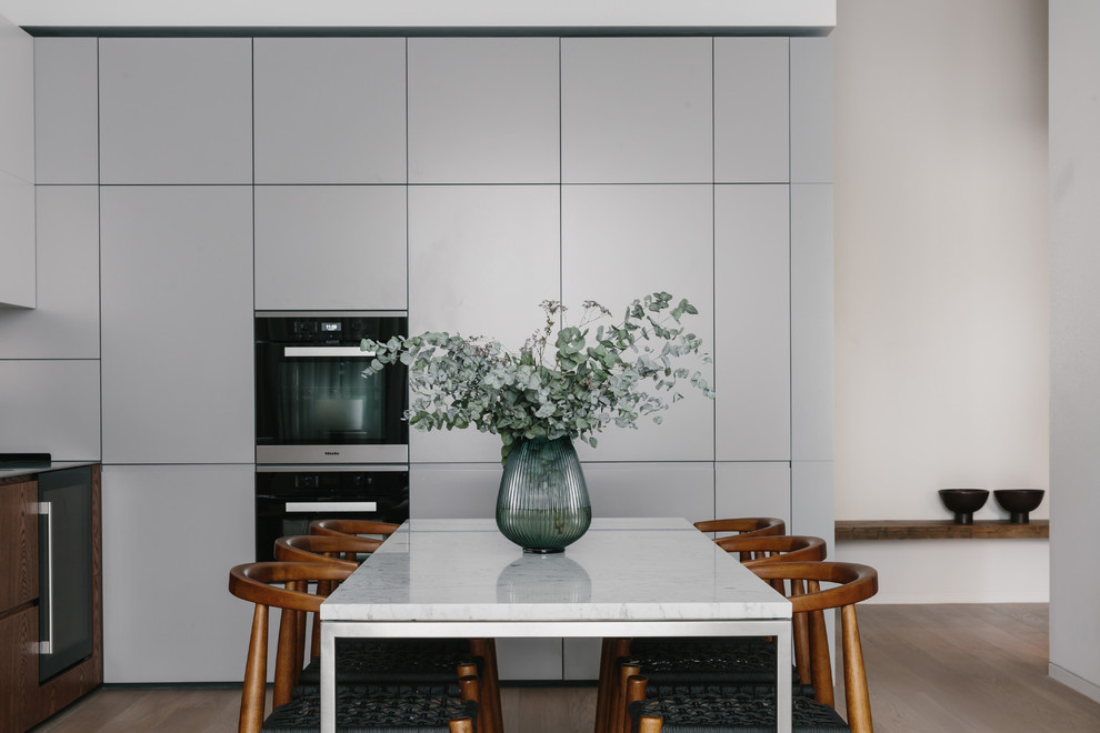 Immagine di una sala da pranzo aperta verso la cucina minimal di medie dimensioni con pareti bianche e parquet chiaro