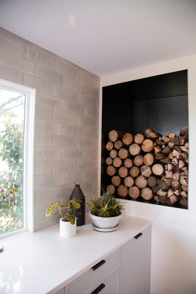 Diseño de comedor de cocina minimalista de tamaño medio con paredes blancas, suelo de madera en tonos medios, todas las chimeneas y marco de chimenea de yeso