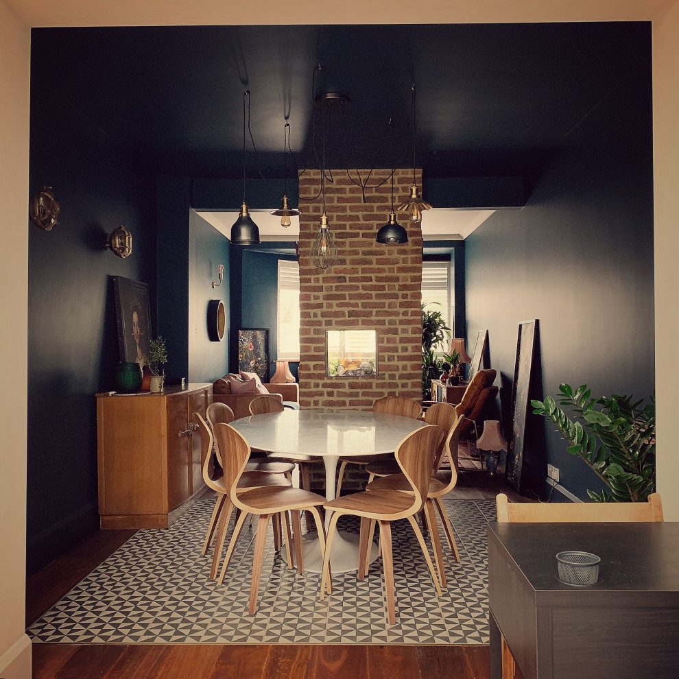 Cette photo montre une petite salle à manger ouverte sur le salon éclectique avec un mur bleu, une cheminée double-face et un manteau de cheminée en brique.