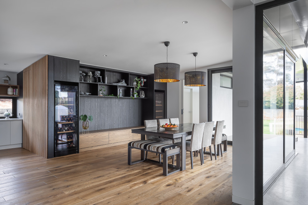 Foto di una sala da pranzo aperta verso la cucina minimal di medie dimensioni con pareti nere, parquet chiaro, nessun camino e pavimento marrone