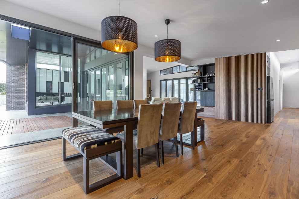 This is an example of a medium sized contemporary kitchen/dining room in Melbourne with black walls and light hardwood flooring.