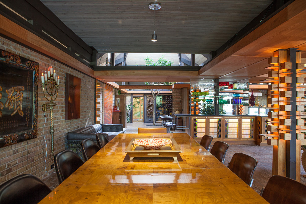 Immagine di una grande sala da pranzo aperta verso il soggiorno eclettica con pareti beige e pavimento in mattoni