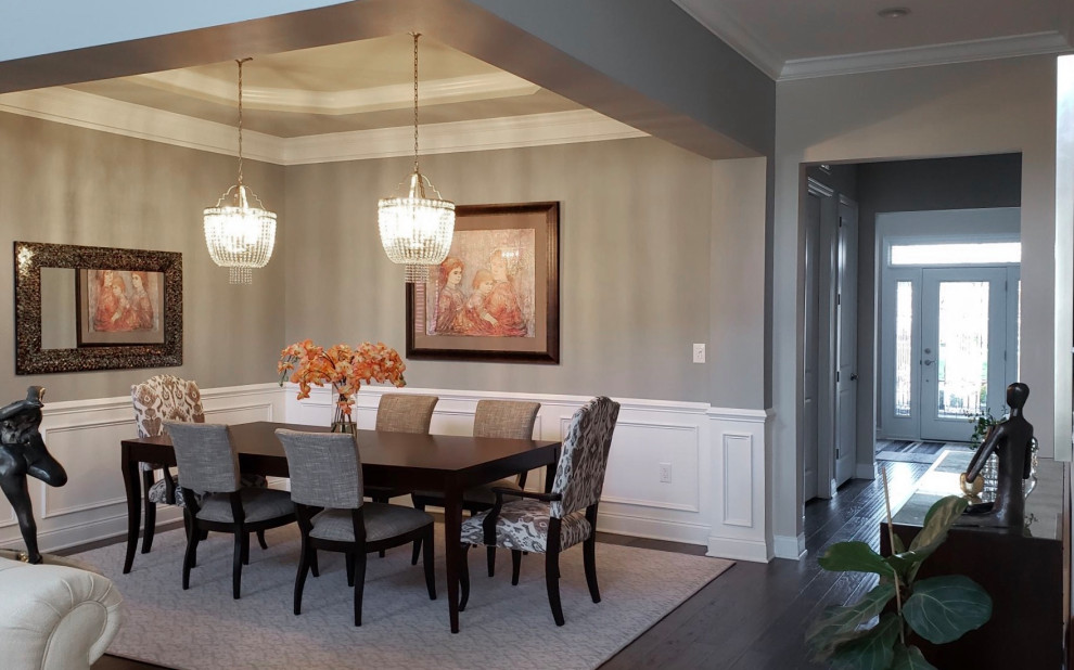 Medium sized classic open plan dining room with grey walls, dark hardwood flooring, no fireplace, brown floors and wainscoting.