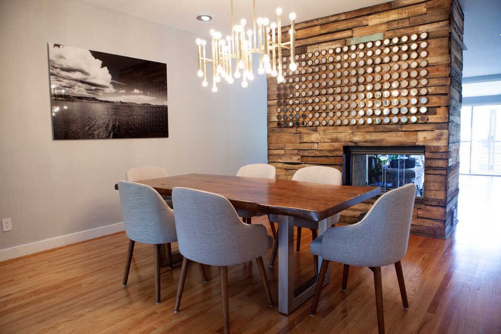 Inspiration for a medium sized contemporary open plan dining room in San Francisco with beige walls, medium hardwood flooring, a standard fireplace and a metal fireplace surround.
