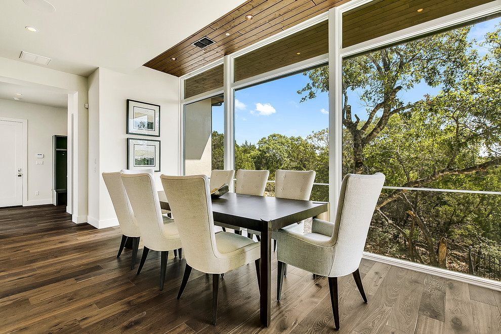 Foto di una grande sala da pranzo aperta verso la cucina minimal con pareti bianche, pavimento in legno massello medio e pavimento marrone