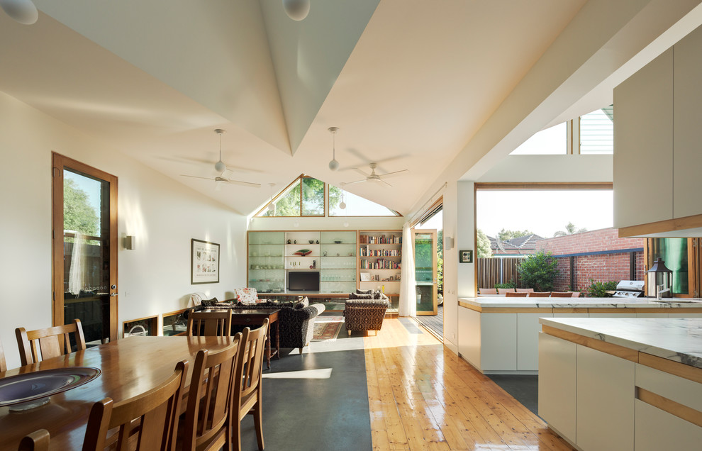 Стильный дизайн: большая гостиная-столовая в современном стиле с белыми стенами и бетонным полом без камина - последний тренд
