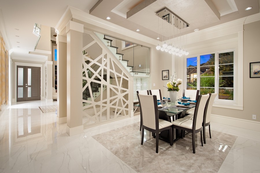 Cette image montre une grande salle à manger ouverte sur la cuisine design avec un mur gris, un manteau de cheminée en pierre et un sol en marbre.
