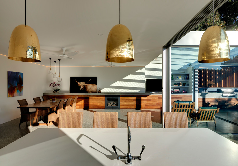 Immagine di una grande sala da pranzo aperta verso il soggiorno design con pareti bianche, pavimento in cemento, camino classico e cornice del camino in legno