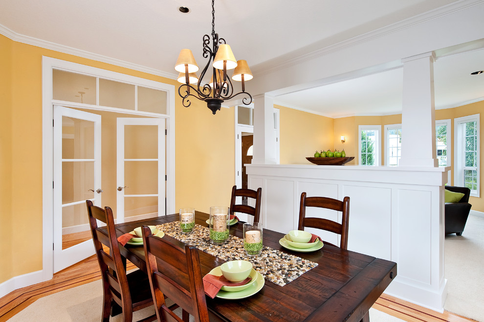 Idée de décoration pour une salle à manger tradition de taille moyenne avec un mur jaune, un sol en bois brun et aucune cheminée.