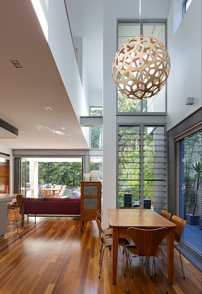 Offenes Modernes Esszimmer ohne Kamin mit weißer Wandfarbe und braunem Holzboden in Brisbane