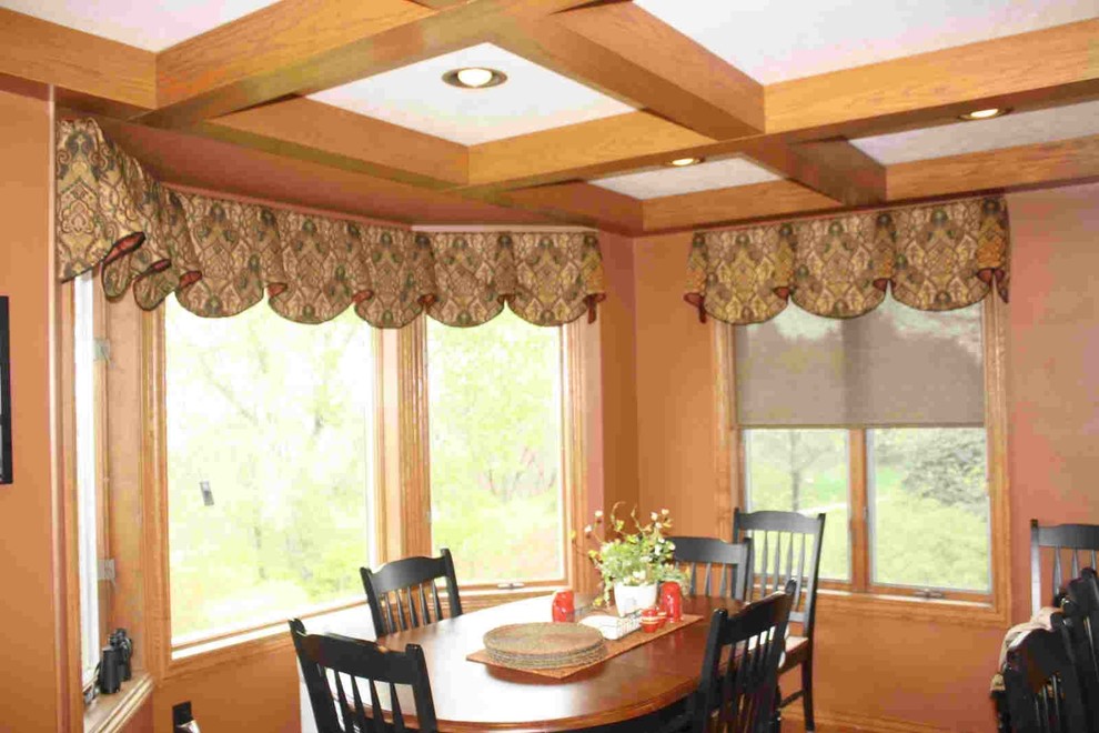 Cette image montre une grande salle à manger ouverte sur la cuisine traditionnelle avec un mur orange et parquet foncé.