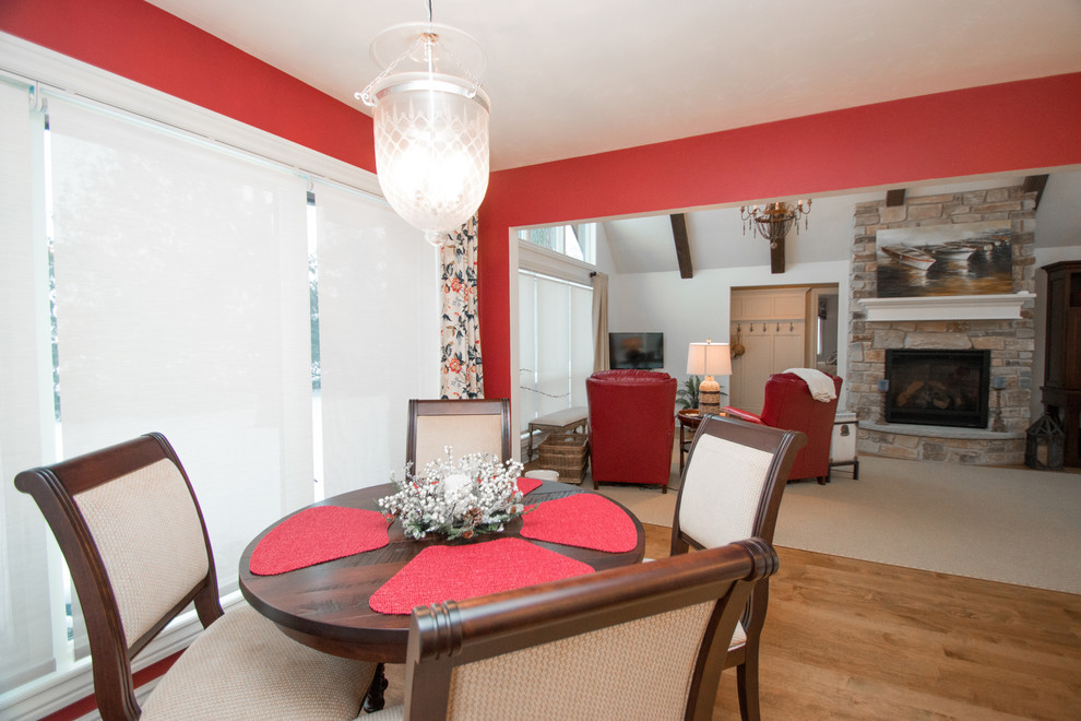Foto di una piccola sala da pranzo aperta verso la cucina tradizionale con pareti rosse, pavimento in legno massello medio e nessun camino