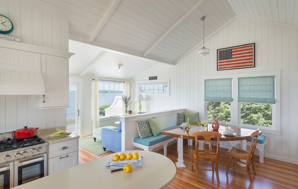 Exemple d'une salle à manger ouverte sur le salon bord de mer avec un sol en bois brun et éclairage.