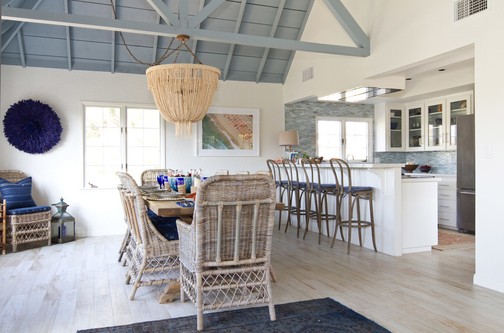 This is an example of a beach style open plan dining room in San Diego with light hardwood flooring, beige floors and feature lighting.