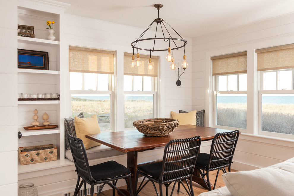 This is an example of a beach style open plan dining room in Boston with white walls and medium hardwood flooring.
