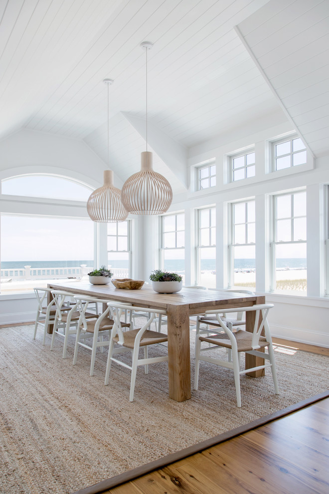 Beach style medium tone wood floor and brown floor dining room photo in New York with white walls