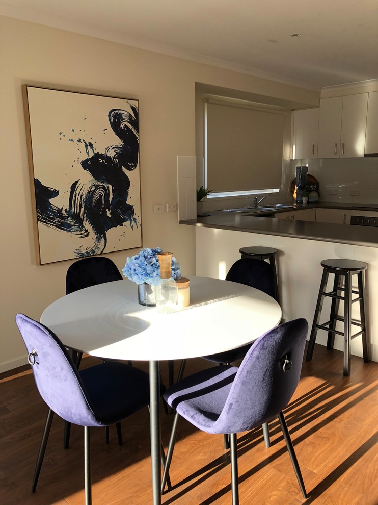 Foto di una piccola sala da pranzo aperta verso il soggiorno stile marinaro con pareti bianche, pavimento in laminato e pavimento marrone
