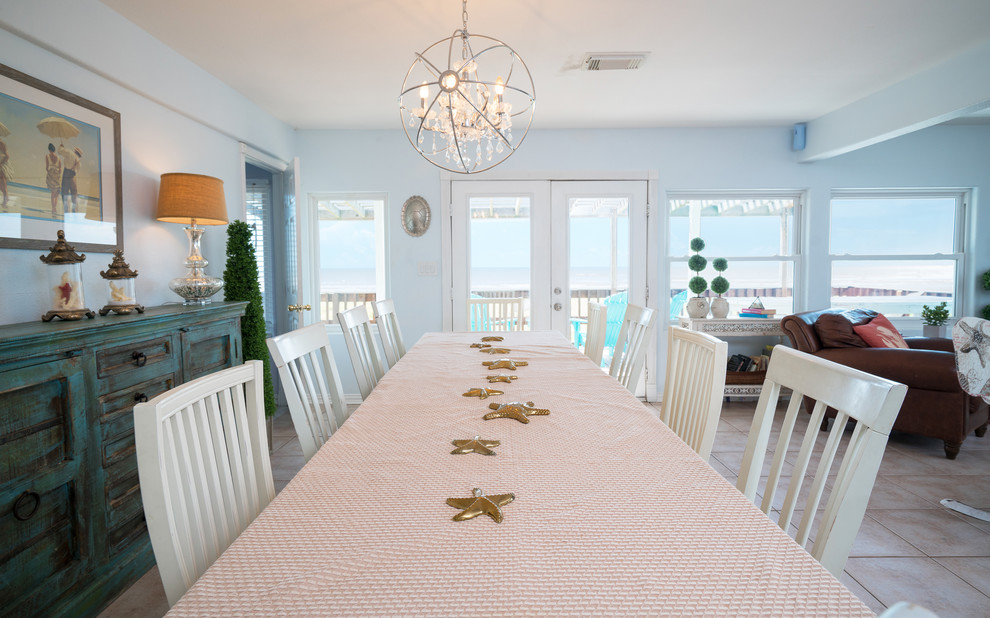 Ispirazione per una piccola sala da pranzo aperta verso la cucina stile marino con pareti blu, pavimento con piastrelle in ceramica, camino ad angolo, cornice del camino in pietra e pavimento beige