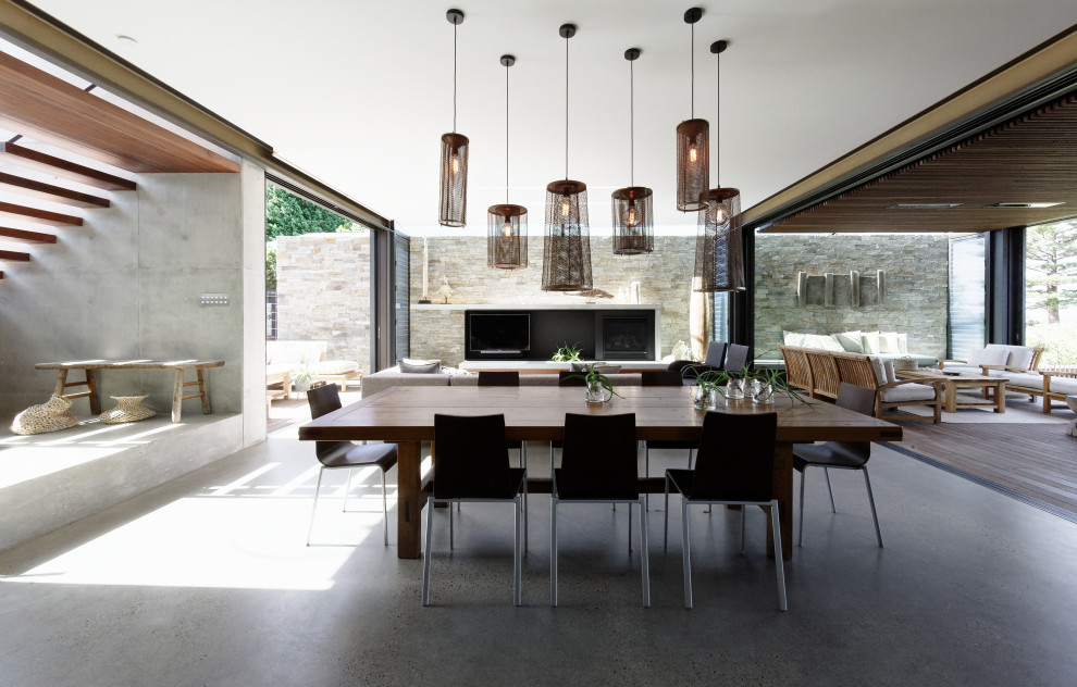 Exemple d'une salle à manger tendance de taille moyenne avec un mur gris, sol en béton ciré, une cheminée standard, un manteau de cheminée en béton et un sol gris.