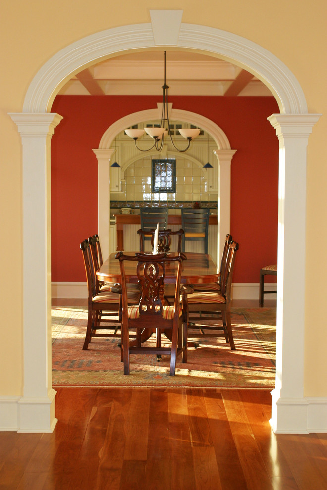 Diseño de comedor clásico de tamaño medio cerrado con paredes rojas y suelo de madera en tonos medios