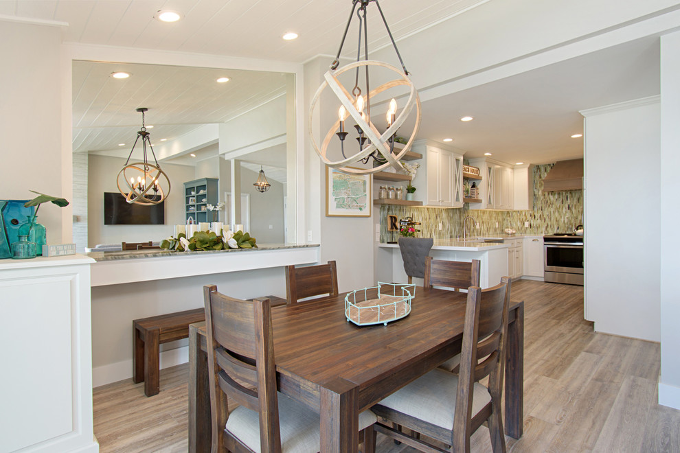 Photo of a medium sized beach style open plan dining room in San Diego with grey walls, vinyl flooring, a standard fireplace, a tiled fireplace surround and grey floors.