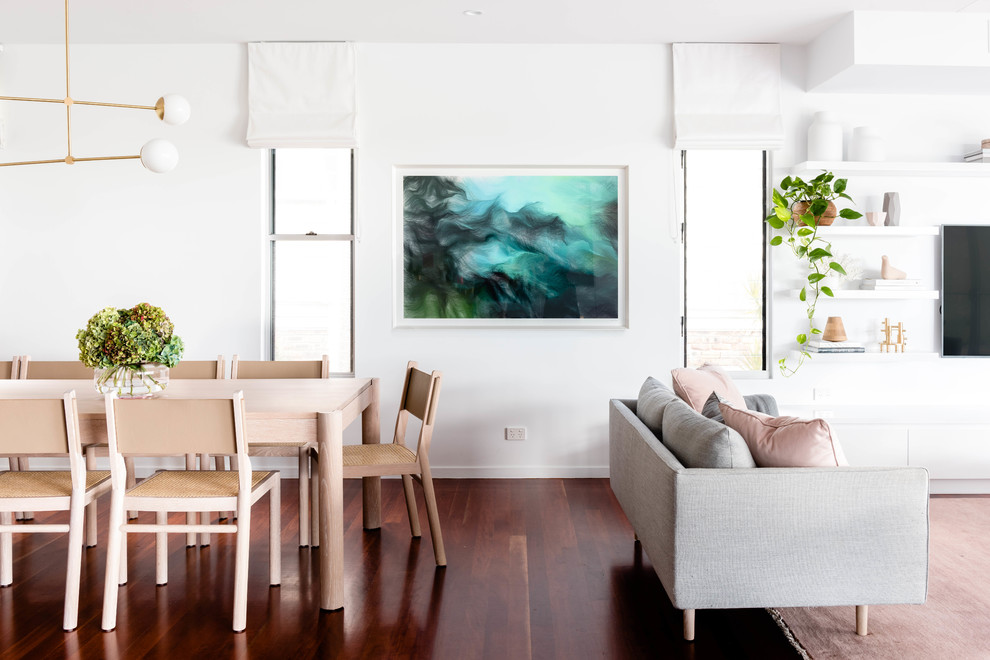 Cette image montre une salle à manger ouverte sur le salon marine avec un mur blanc, parquet foncé et un sol marron.